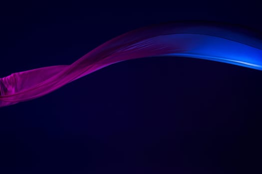 Smooth elegant transparent blue cloth isolated or separated on dark blue studio background. Texture of flying silk fabric.