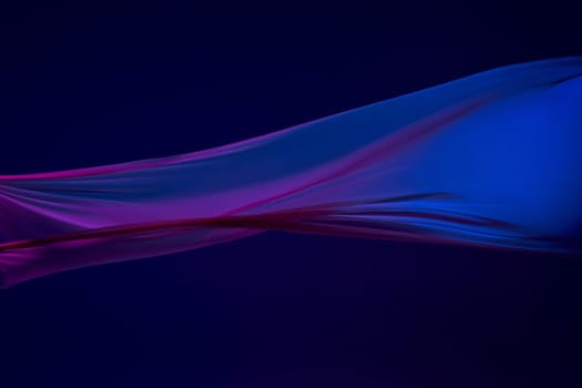 Smooth elegant transparent blue cloth isolated or separated on dark blue studio background. Texture of flying silk fabric.