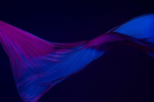 Smooth elegant transparent blue cloth isolated or separated on dark blue studio background. Texture of flying silk fabric.