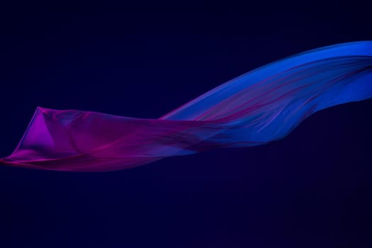 Smooth elegant transparent blue cloth isolated or separated on dark blue studio background. Texture of flying silk fabric.