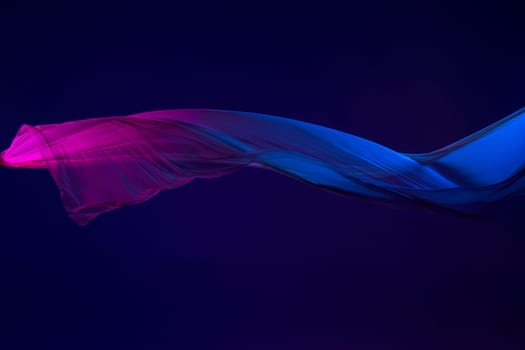 Smooth elegant transparent blue cloth isolated or separated on dark blue studio background. Texture of flying silk fabric.