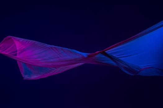 Smooth elegant transparent blue cloth isolated or separated on dark blue studio background. Texture of flying silk fabric.