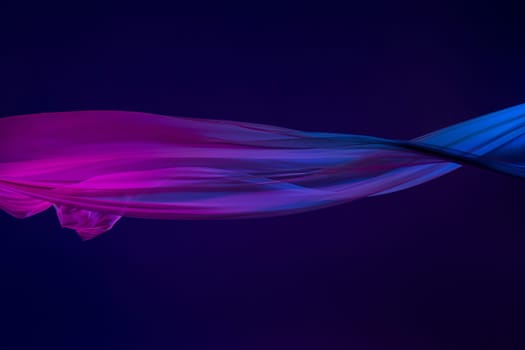 Smooth elegant transparent blue cloth isolated or separated on dark blue studio background. Texture of flying silk fabric.