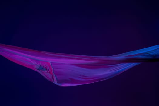 Smooth elegant transparent blue cloth isolated or separated on dark blue studio background. Texture of flying silk fabric.