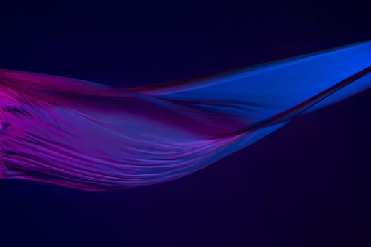Smooth elegant transparent blue cloth isolated or separated on dark blue studio background. Texture of flying silk fabric.