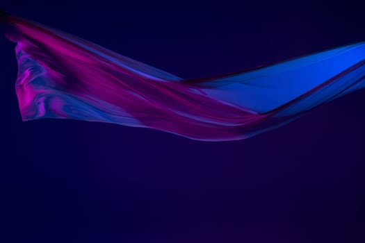 Smooth elegant transparent blue cloth isolated or separated on dark blue studio background. Texture of flying silk fabric.