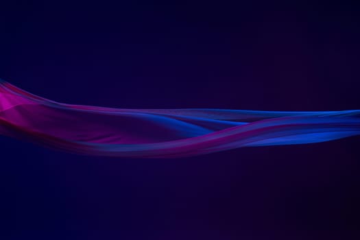 Smooth elegant transparent blue cloth isolated or separated on dark blue studio background. Texture of flying silk fabric.