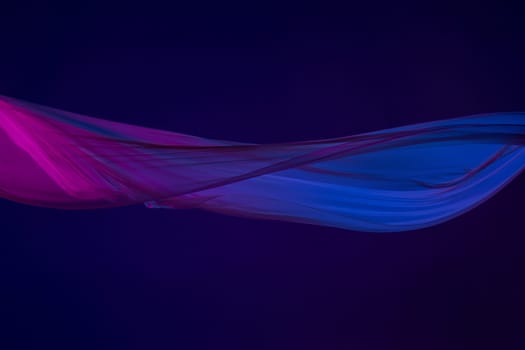 Smooth elegant transparent blue cloth isolated or separated on dark blue studio background. Texture of flying silk fabric.