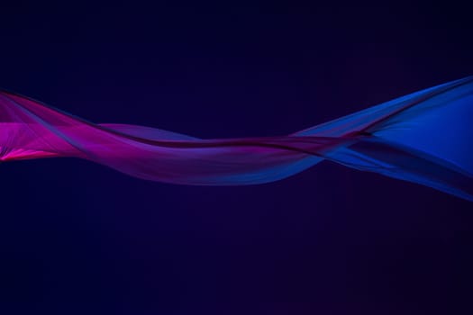 Smooth elegant transparent blue cloth isolated or separated on dark blue studio background. Texture of flying silk fabric.