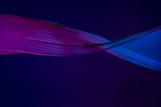 Smooth elegant transparent blue cloth isolated or separated on dark blue studio background. Texture of flying silk fabric.