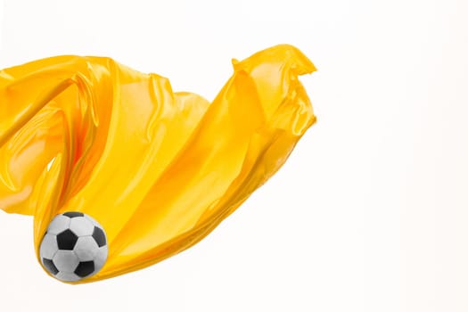 Soccer ball and Smooth elegant transparent yellow cloth isolated or separated on white studio background. Texture of flying fabric. yellow. Attributes of popular game. Concept of national flag color