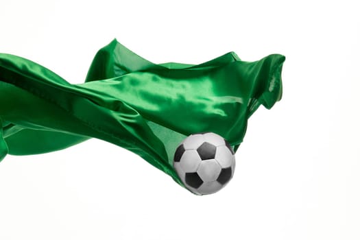 Soccer ball and Smooth elegant transparent green cloth isolated or separated on white studio background. Texture of flying fabric. yellow. Attributes of popular game. Concept of national flag color