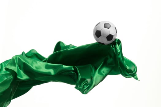 Soccer ball and Smooth elegant transparent green cloth isolated or separated on white studio background. Texture of flying fabric. yellow. Attributes of popular game. Concept of national flag color