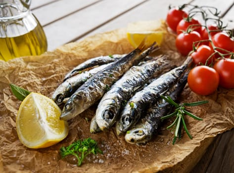 Fried sardines with lemon and salad close up.