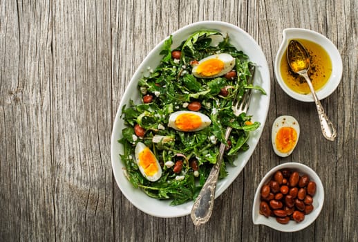 Fresh healthy dandelion salad with eggs and beans overhead shoot