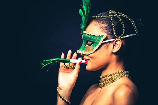 Upscale Indian woman wearing gold jewellery and red lipstick on black background. Green party mask.