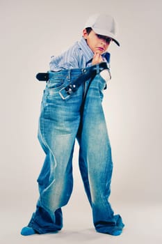 Caucasian boy wearing his Dad's shirt, jeans and tie on light background. He is wearing big adult size clothes which are too big for him.