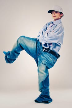 Caucasian boy wearing his Dad's shirt, jeans and tie on light background. He is wearing big adult size clothes which are too big for him.