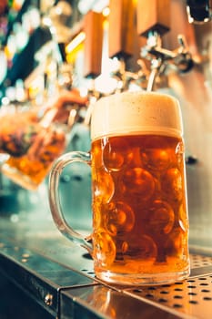 We meet oktoberfest. Hand of bartender pouring a large lager beer in tap. Pouring beer for client. Side view of young bartender pouring beer while standing at the bar counter