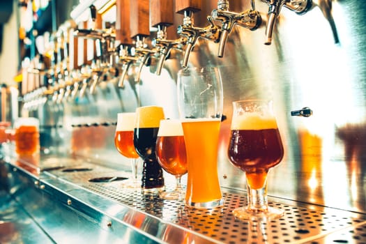 The beer taps in a pub. nobody. Selective focus. Alcohol concept. Vintage style. Beer craft. Bar table. Steel taps. Shiny taps. Glass of beer