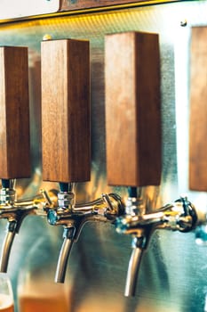 The beer taps in a pub. nobody. Selective focus. Alcohol concept. Vintage style. Beer craft. Bar table. Steel taps. Shiny taps. Glass of beer