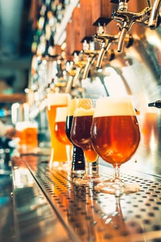 The beer taps in a pub. nobody. Selective focus. Alcohol concept. Vintage style. Beer craft. Bar table. Steel taps. Shiny taps. Glass of beer
