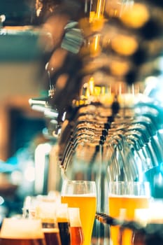 The beer taps in a pub. nobody. Selective focus. Alcohol concept. Vintage style. Beer craft. Bar table. Steel taps. Shiny taps. Glass of beer