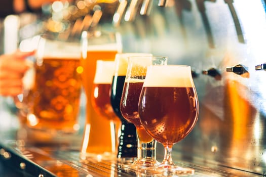 The beer taps in a pub. nobody. Selective focus. Alcohol concept. Vintage style. Beer craft. Bar table. Steel taps. Shiny taps. Glass of beer. Octoberfest concept