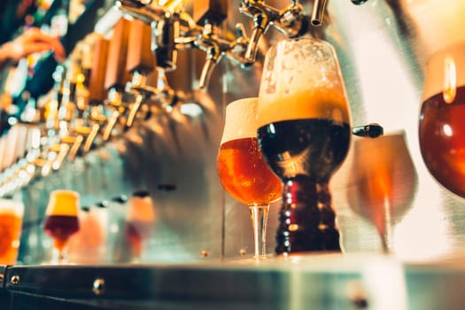 Hand of bartender pouring a large lager beer in tap. Soft, vintage instagram effect on photo