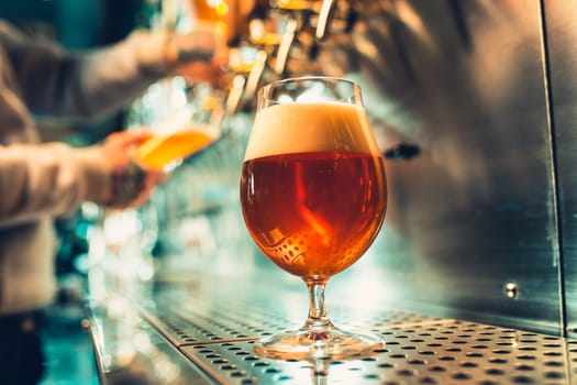 Hand of bartender pouring a large lager beer in tap. Soft, vintage instagram effect on photo. Pouring beer for client. Side view of young bartender pouring beer while standing at the bar counter