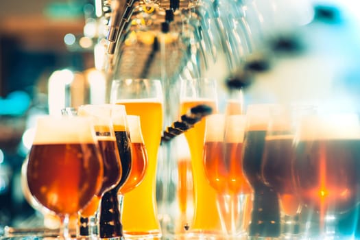 The beer taps in a pub. nobody. Selective focus. Alcohol concept. Vintage style. Beer craft. Bar table. Steel taps. Shiny taps. Glass of beer