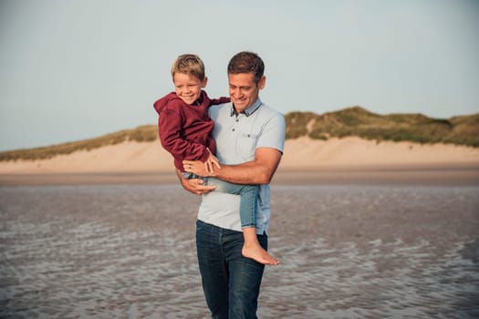 Father and son spending some time together, walking down the beach on holiday.