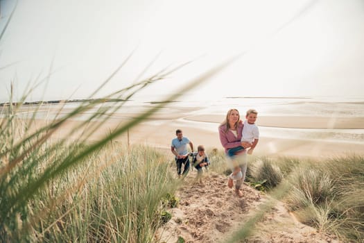 Family with two little boys walking up the sand dune.