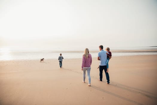 Rear View of family with two children walking down to the waters edge while on holiday.