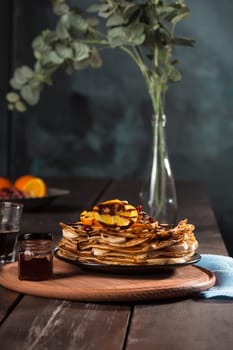 Fresh homemade french crepes made with ffresh fruits on a vintage wooden board on the wooden table. Side view with honey, fruits and coffee. French pancakes concept