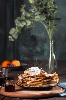 Fresh homemade french crepes made with ffresh fruits on a vintage wooden board on the wooden table. Side view with honey, fruits and coffee. French pancakes concept