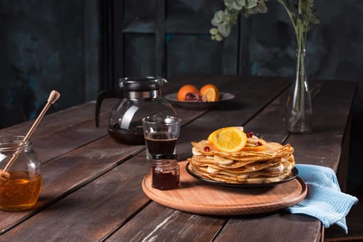 Fresh homemade french crepes made with ffresh fruits on a vintage wooden board on the wooden table. Side view with honey, fruits and coffee. French pancakes concept