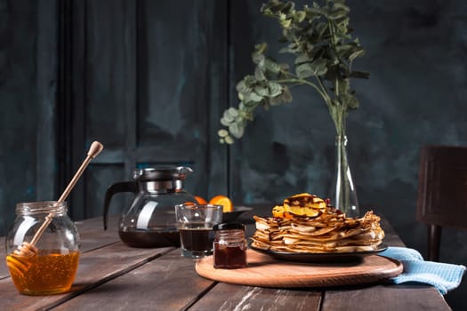 Fresh homemade french crepes made with ffresh fruits on a vintage wooden board on the wooden table. Side view with honey, fruits and coffee. French pancakes concept