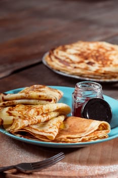 Fresh homemade french crepes made with ffresh fruits on a vintage wooden board on the wooden table. Side view with honey, fruits and coffee. French pancakes concept
