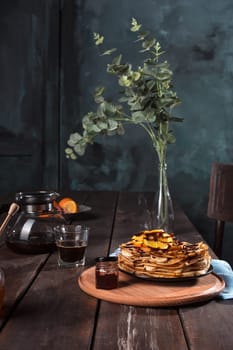 Fresh homemade french crepes made with ffresh fruits on a vintage wooden board on the wooden table. Side view with honey, fruits and coffee. French pancakes concept