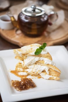 Honey cake with vanilla cream at white plate