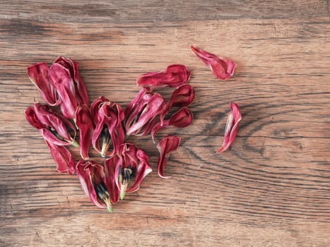 Heart shape of dried tulips petals on a rustic wooden table using as background