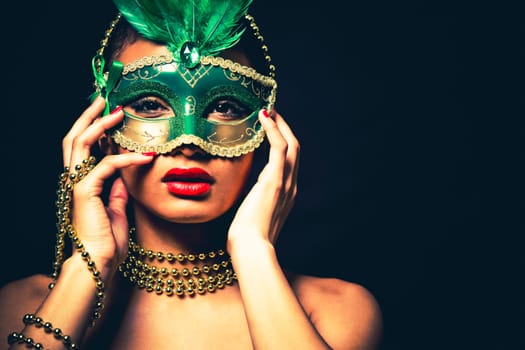 Upscale Indian woman wearing gold jewellery and red lipstick on black background. Green party mask.