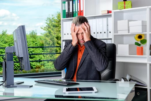 young tired business man with head in hands is over-worked