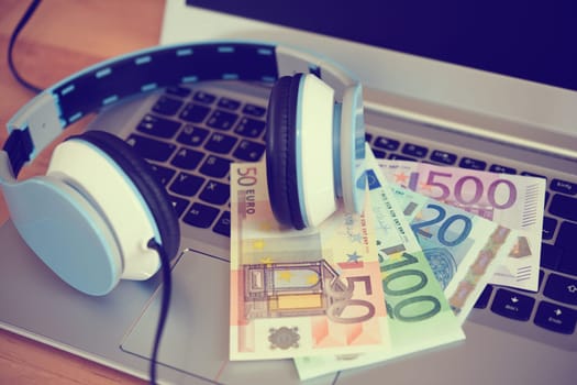 computer keyboard with headphones and dollar bank notes