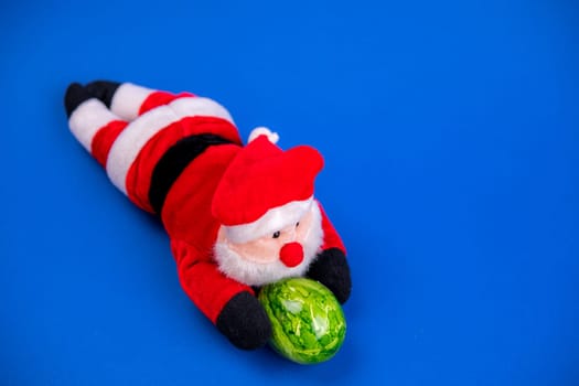 little santa claus with green easter egg on blue ground