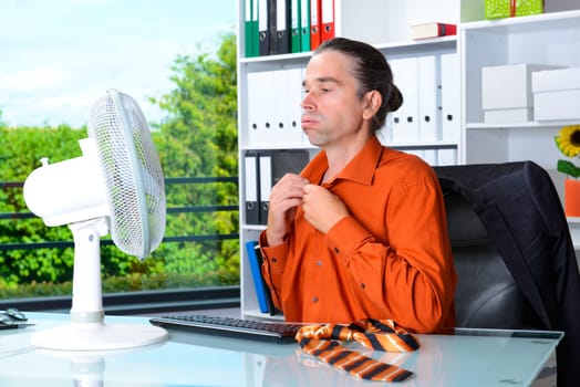 business man with ventilator at his desk in summerly hot office