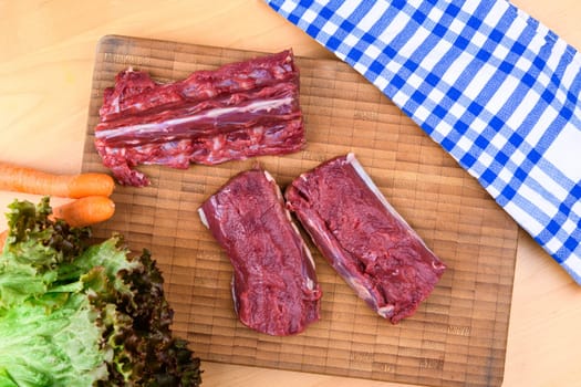 saddle of venison on wooden board with big knife