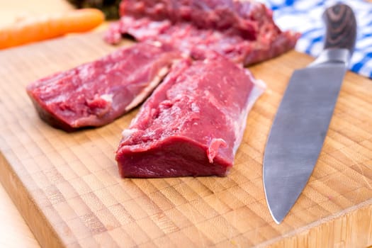 saddle of venison on wooden board with big knife