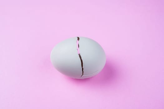 broken egg with crack on pink ground